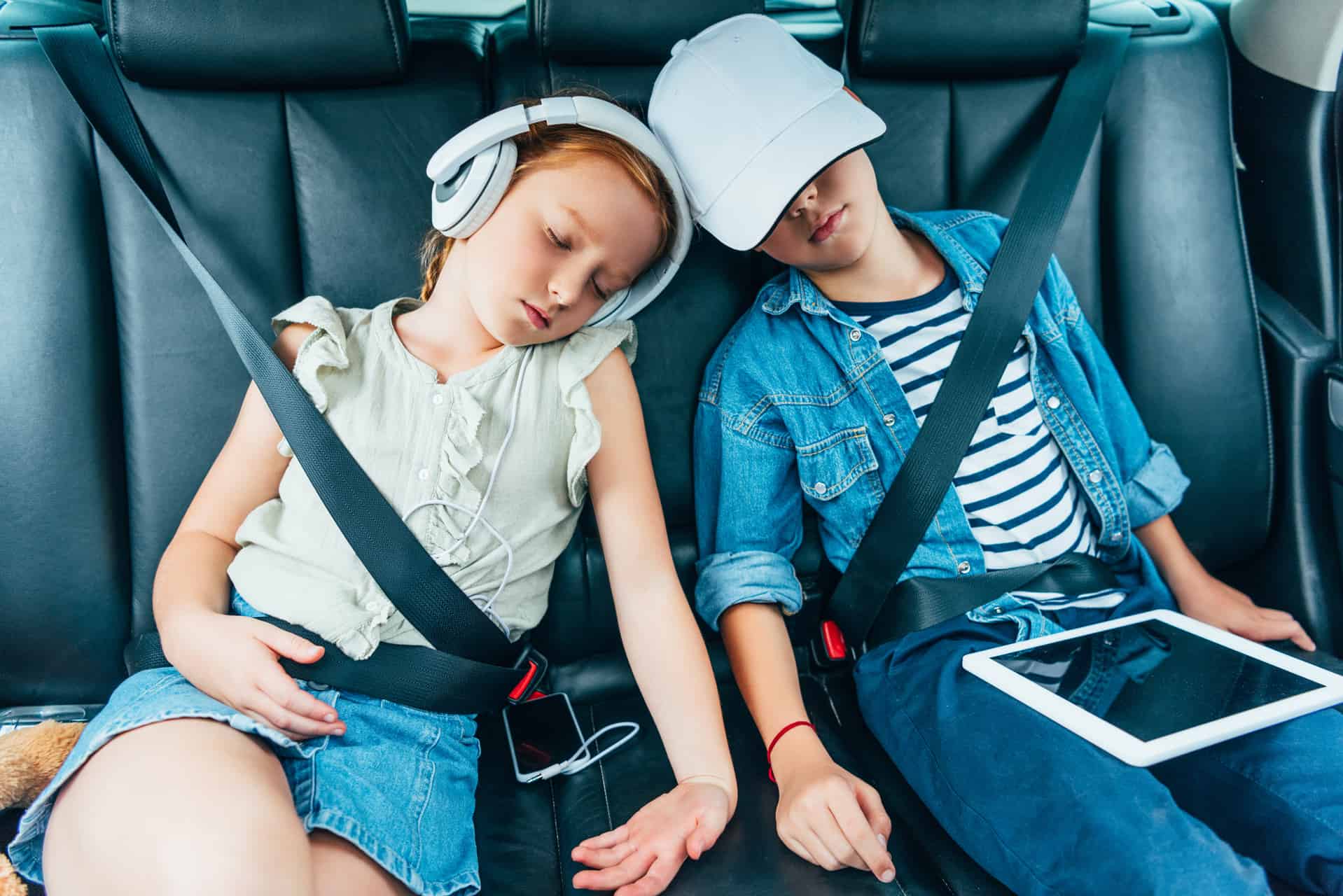 To Børn Sover På Bagsædet Af En Bil Med Smartphone Ipad Og Høretelefoner Ferie